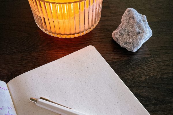 Intuitiv skrift. Under andliga tjänster syns ett block och en penna framför en kristall och ett tänt ljus.